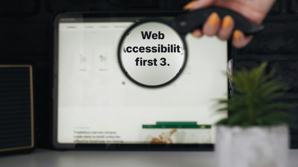 돋보기로 태블릿 화면을 확대해 'Web Accessibility first 3.' 문구를 보여주는 사진